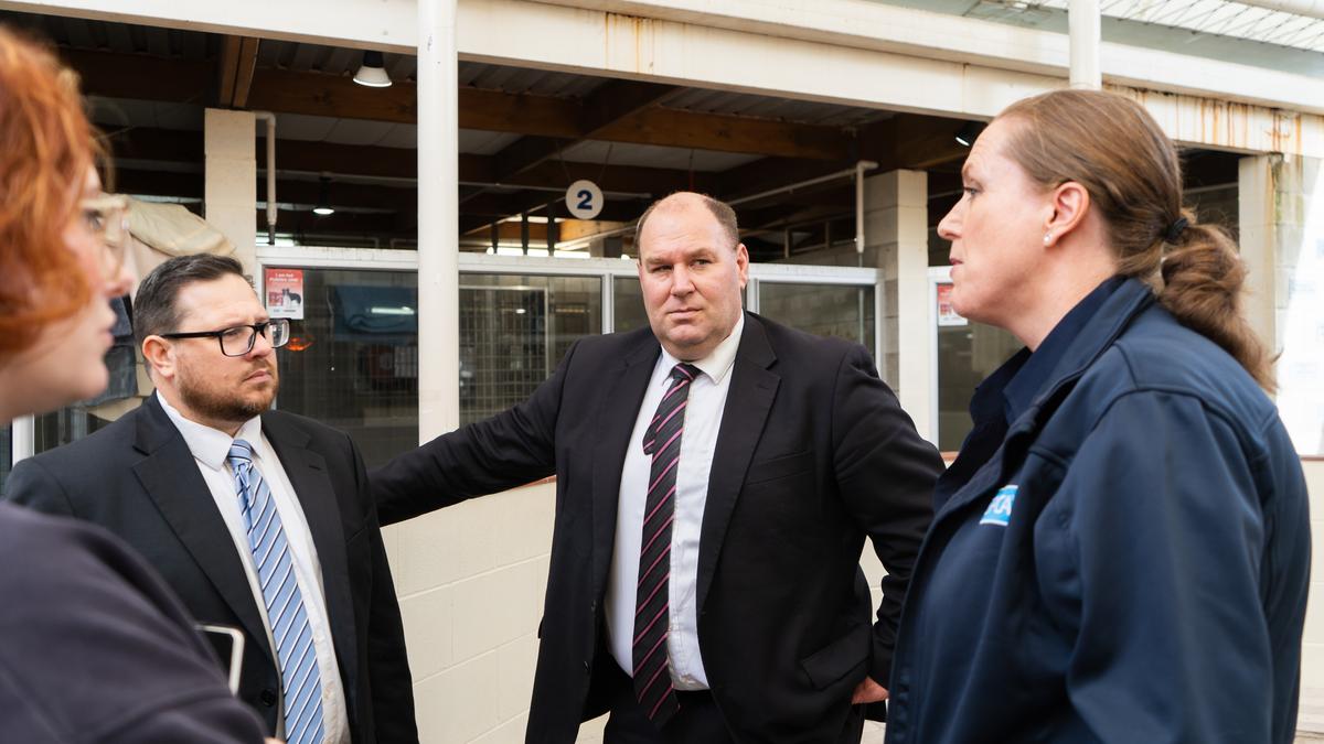 Four people stand in a circle talking. The Minister leans on a wall while listening to Dr. Dale speak.