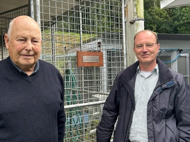 Two men standing in front of a dog run